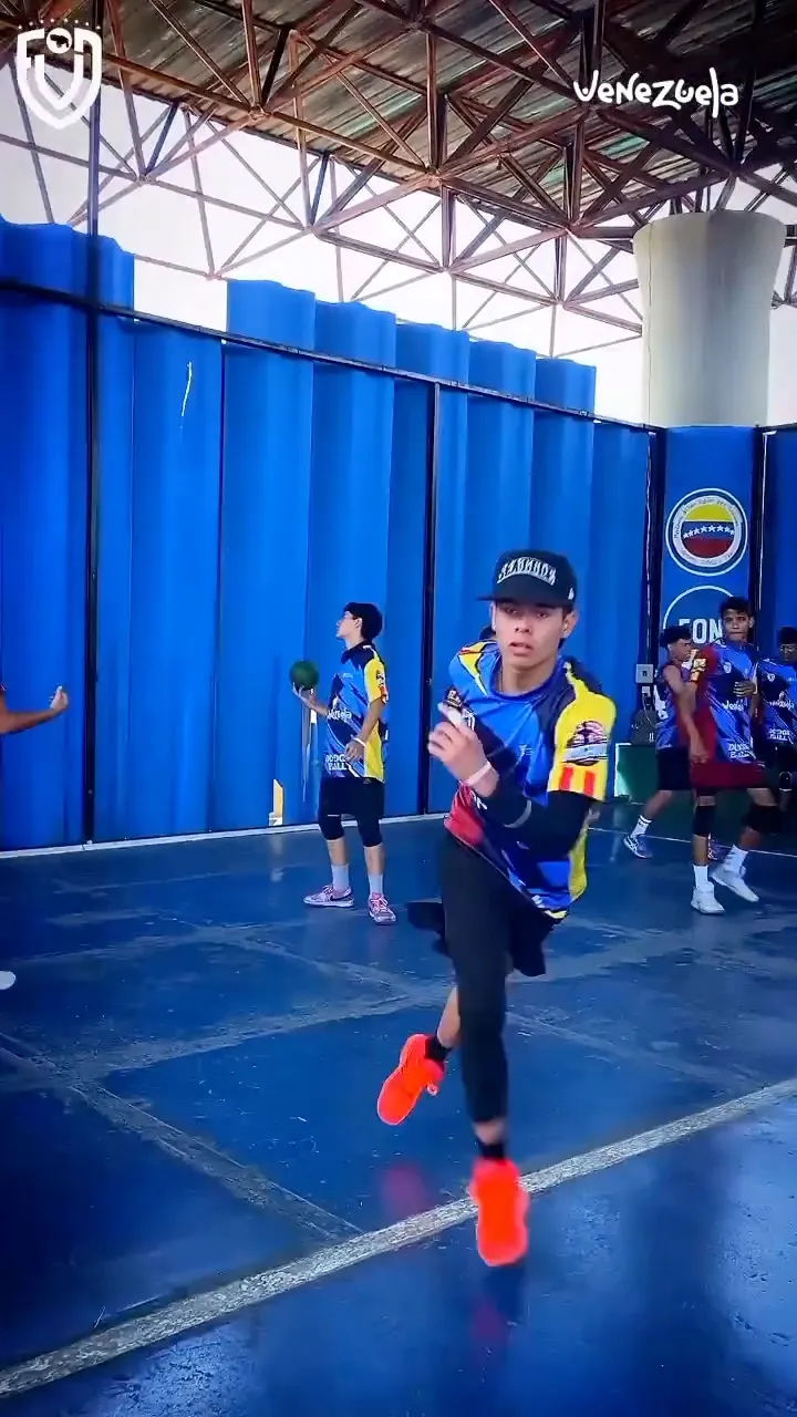 Un jugador lanza el balón a toda velocidad mientras sus compañeros esperan al fondo de la cancha